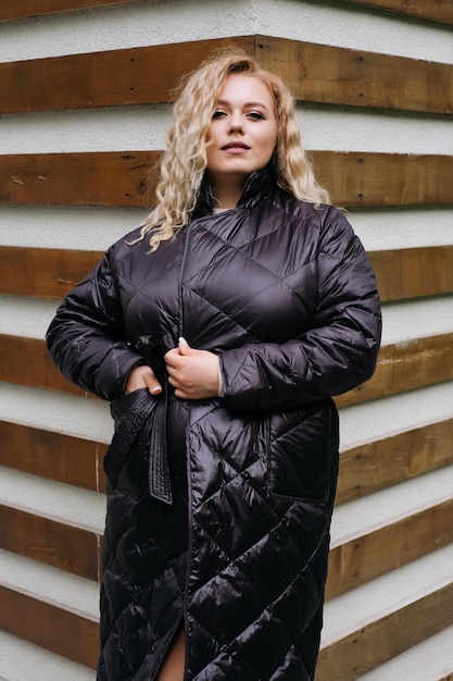 Mulher loira na moda casaco acolchoado preto modelo de banner de publicidade de passeio na cidade de grandes dimensões tamanho grande