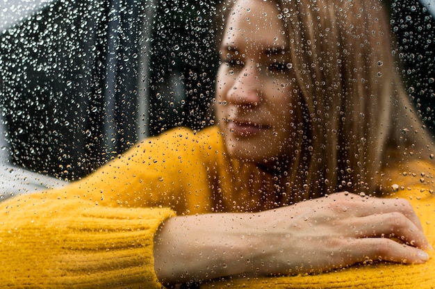 Mulher loira olhando a chuva pela janela