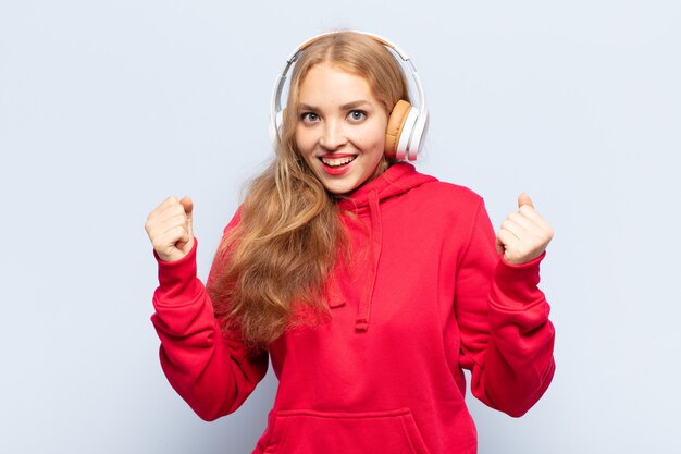 Mulher loira se sentindo chocada, animada e feliz, rindo e comemorando o sucesso, dizendo uau!