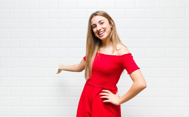 Mulher loira se sentindo feliz e alegre, sorrindo e dando as boas-vindas, convidando-o com um gesto amigável