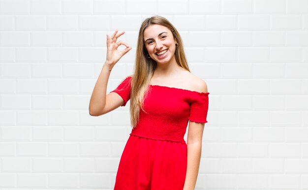 Mulher loira se sentindo feliz, relaxada e satisfeita, mostrando aprovação com gesto de ok, sorrindo