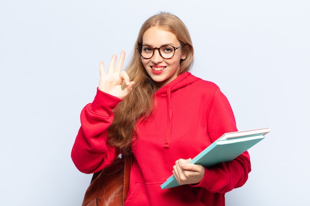 Mulher loira se sentindo feliz, relaxada e satisfeita, mostrando aprovação com gesto de ok, sorrindo