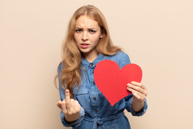 Mulher loira se sentindo irritada, irritada, rebelde e agressiva, sacudindo o dedo do meio e lutando