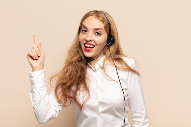 Mulher loira se sentindo um gênio feliz e empolgado depois de realizar uma ideia, levantando alegremente o dedo, eureka!