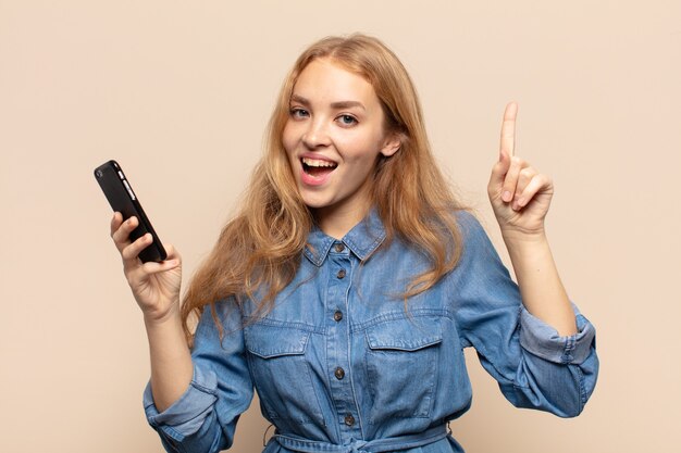 Mulher loira se sentindo um gênio feliz e empolgado depois de realizar uma ideia, levantando alegremente o dedo, eureka!