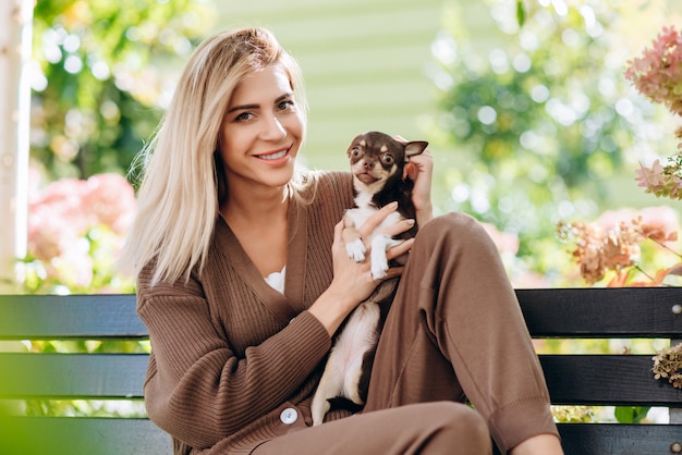 Foto mulher loira, segurando nas mãos seu animal de estimação e abraçando-o