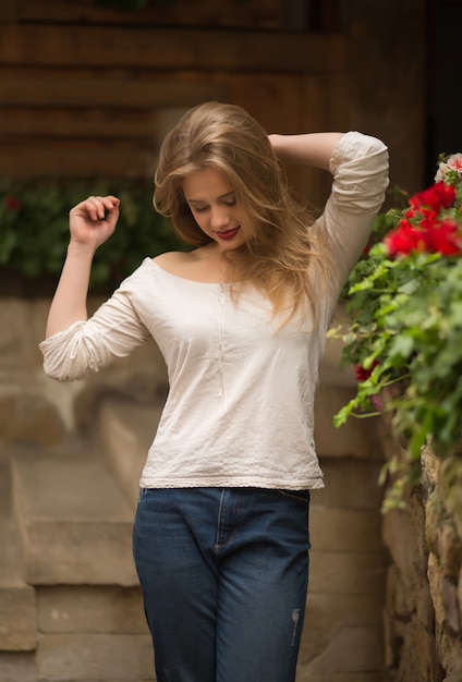 Mulher loira sensual usando roupas da moda, posando na rua com flores em Lviv