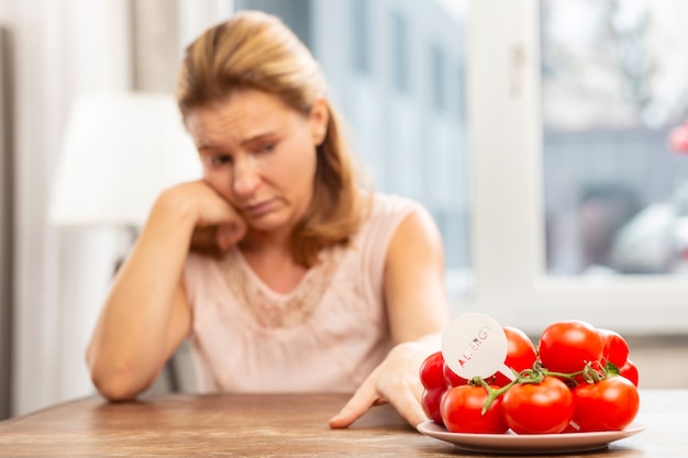 Mulher loira sentindo-se desconfortável por ter alergia a tomate