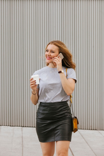 Mulher loira sexy falando ao telefone enquanto bebe café