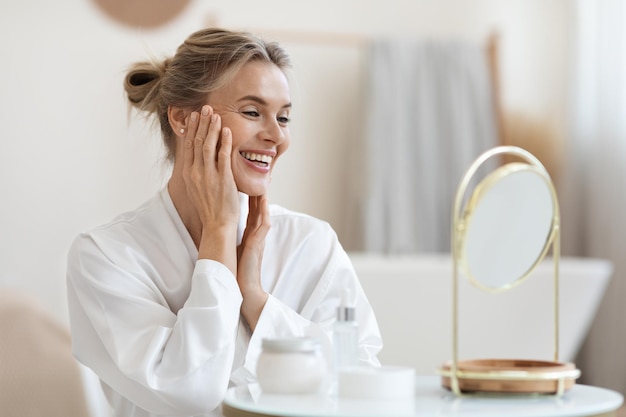 Mulher loira sorridente fazendo massagem facial antienvelhecimento