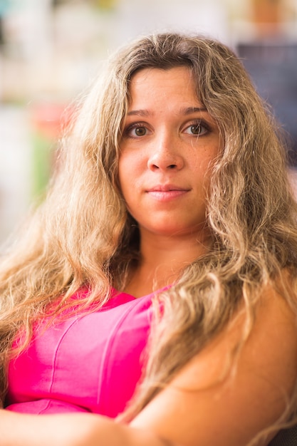 Mulher loira sorridente no vestido rosa, sentado na cadeira