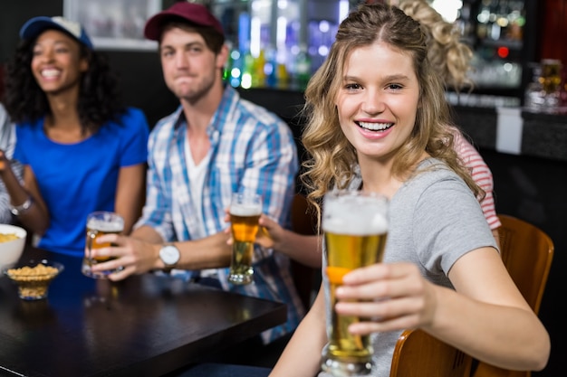 Mulher loira sorridente oferecendo cerveja