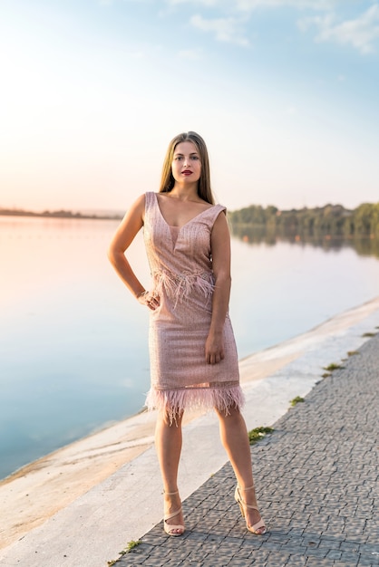 Mulher loira sorridente posando em vestido de moda na praia