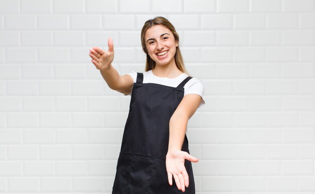 Mulher loira sorrindo alegremente dando um abraço caloroso, amigável e afetuoso de boas-vindas, sentindo-se feliz e adorável