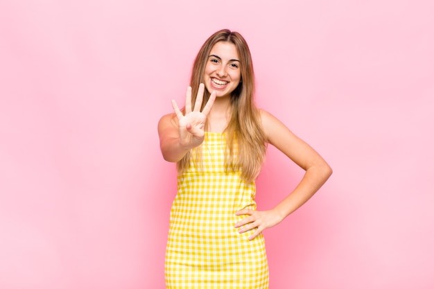 Mulher loira sorrindo e parecendo amigável, mostrando o número quatro ou o quarto com a mão para a frente, em contagem regressiva