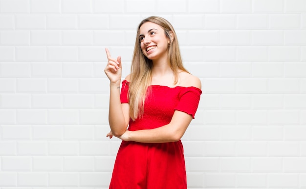 Mulher loira sorrindo feliz e olhando de soslaio, pensando, pensando ou tendo uma ideia