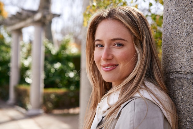 Mulher loira sorrindo no parque aproveitando a pausa mental