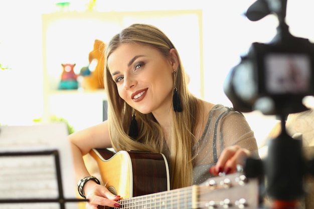 Mulher loira tocando violão ao vivo na câmera