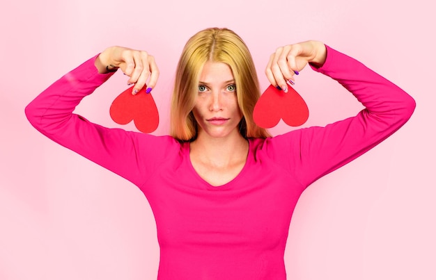 Mulher loira triste do dia dos namorados com dois corações de papel vermelho amor infeliz quebra de relações