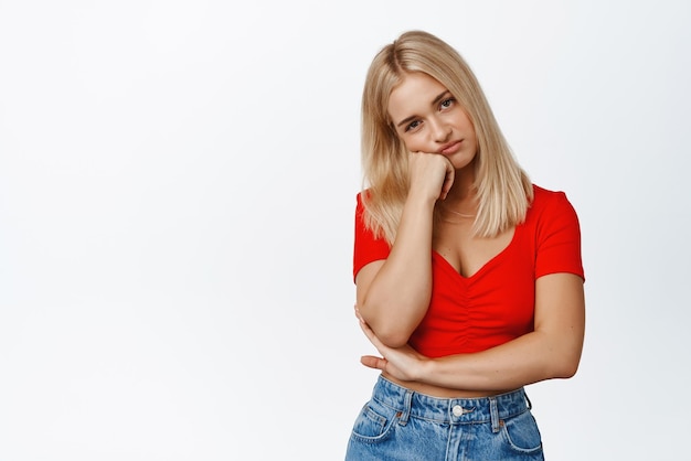 Mulher loira triste e entediada com a cabeça no punho olhando com expressão de rosto não divertido e relutante fundo branco