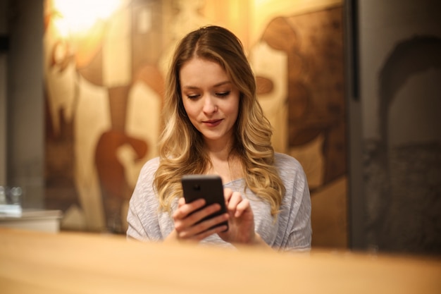 Mulher loira, verificando seu smartphone