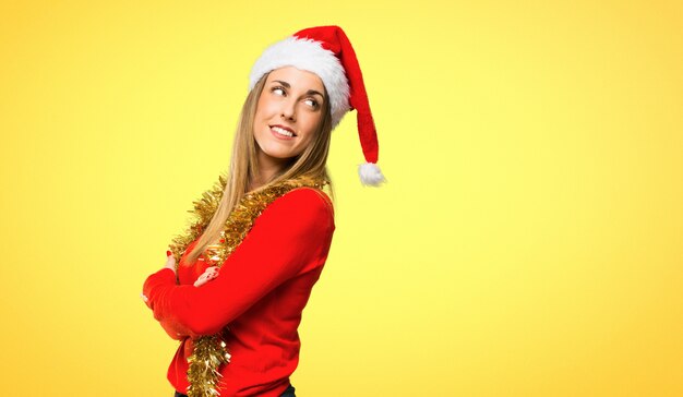 Mulher loira vestida para férias de natal, olhando por cima do ombro com um sorriso