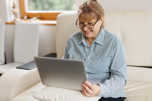 Mulher madura ativa usando um laptop para trabalho remoto no escritório doméstico Videoconferência videoconferência Professor sênior lidera webinar