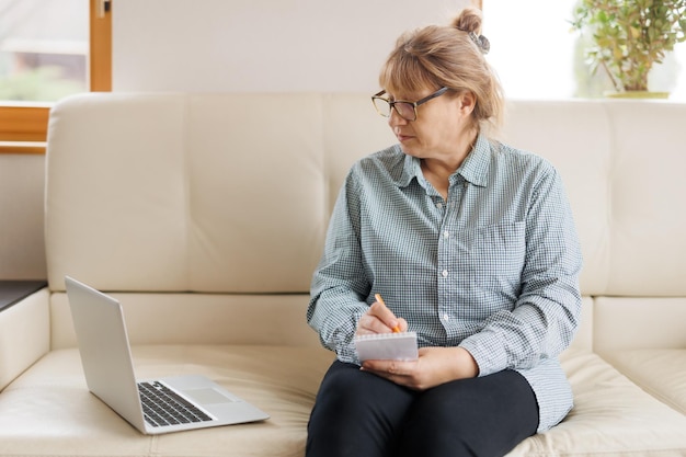 Mulher madura ativa usando um laptop para trabalho remoto no escritório doméstico Videoconferência videoconferência Professor sênior lidera webinar