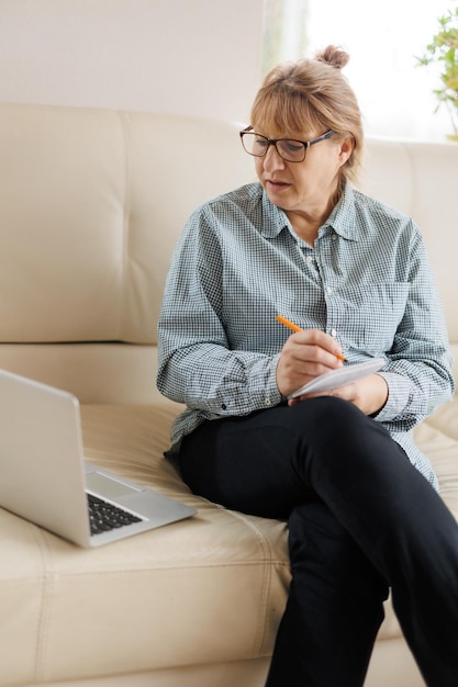 Mulher madura ativa usando um laptop para trabalho remoto no escritório doméstico Videoconferência videoconferência Professor sênior lidera webinar