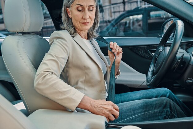 Mulher madura bonita em roupa casual inteligente ajustando o cinto de segurança