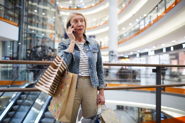 Mulher madura, chamando o amigo no shopping