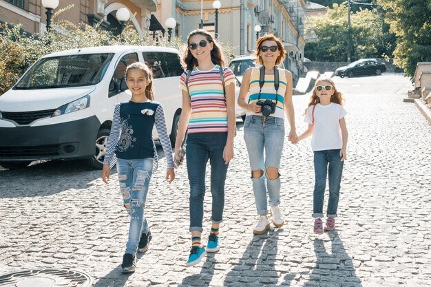 Mulher madura com crianças andando em uma rua da cidade em dia de sol de verão