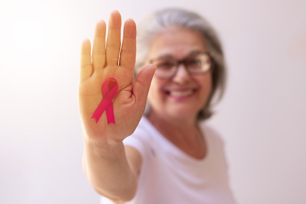 Mulher madura com uma fita rosa isolada no branco. Imagem do mês de conscientização do câncer de mama.