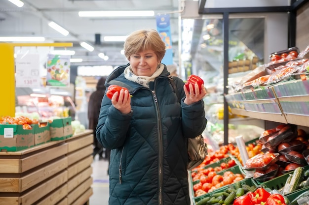 Mulher madura comprando legumes no mercado de agricultores