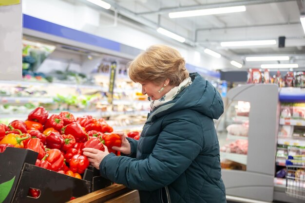 Mulher madura comprando legumes no mercado de agricultores