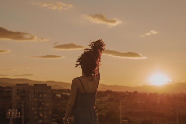 Foto mulher madura de pé no terraço contra durante o pôr do sol