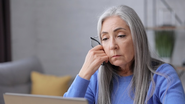 Mulher madura deprimida recebeu más notícias online. Síndrome de burnout, excesso de trabalho, depressão.