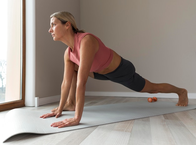 Mulher madura desportiva com regata rosa a fazer exercícios de treino