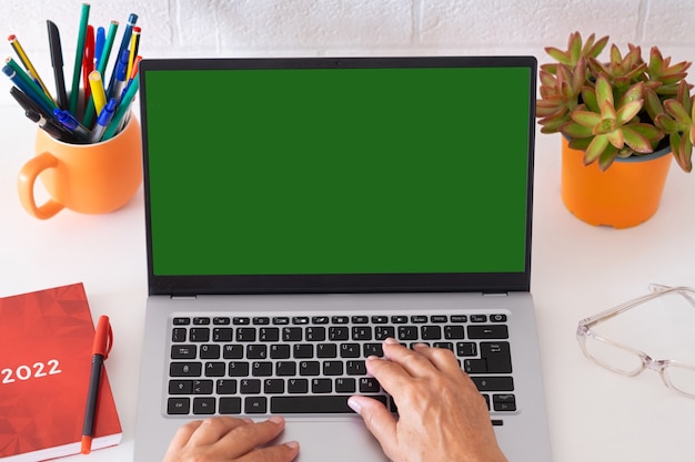 Mulher madura digitando no teclado usando um laptop Área de trabalho branca e parede de tijolos Trabalho social