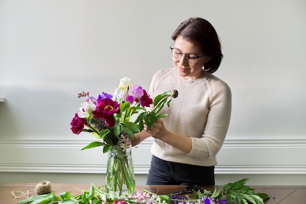 Mulher madura em casa com flores da primavera