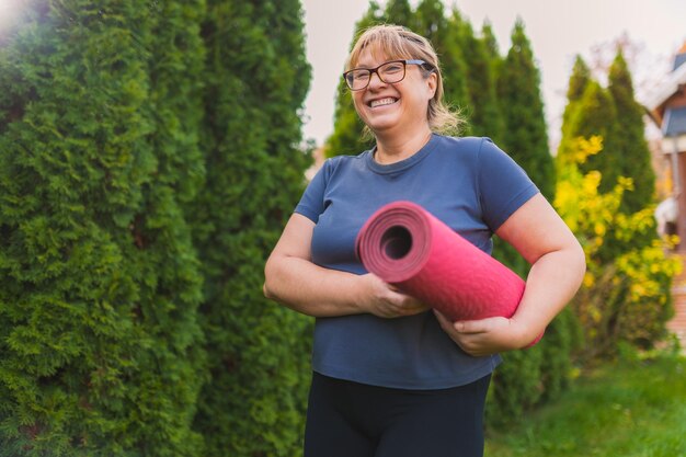 Mulher madura em retiro de ioga ao ar livre caminhando ao longo do caminho através do acampamento