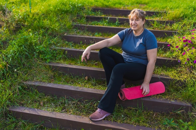 Mulher madura em retiro de ioga ao ar livre caminhando ao longo do caminho através do acampamento