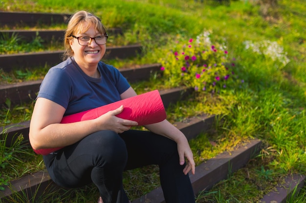 Mulher madura em retiro de ioga ao ar livre caminhando ao longo do caminho através do acampamento