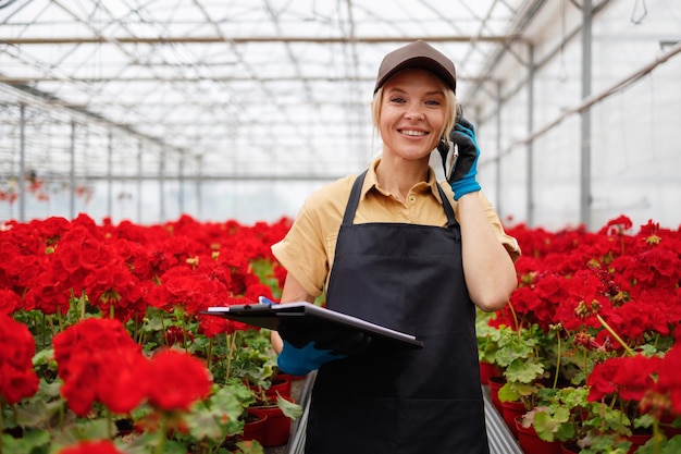 Mulher madura empregada em estufa com flores falando no celular