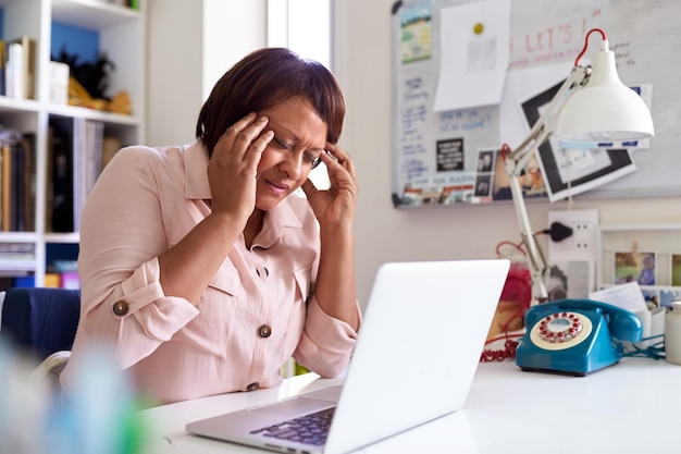 Foto mulher madura estressada com laptop trabalhando em home office