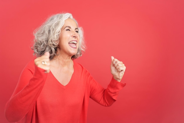 Mulher madura excitada comemorando enquanto levanta os punhos