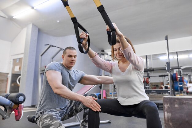Mulher madura, exercitando-se no ginásio usando loops de tiras de fitness