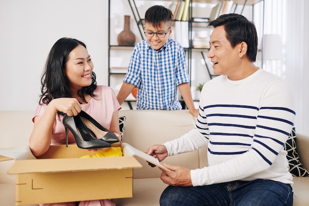 Mulher madura feliz abrindo um presente de aniversário do marido e do filho e tirando sapatos de salto novos