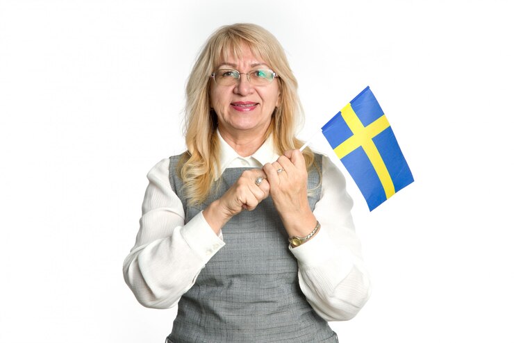 Mulher madura feliz com a bandeira da Suécia em pé sobre um fundo branco.