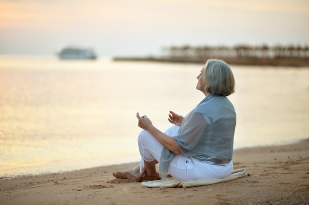 Mulher madura feliz meditando na praia